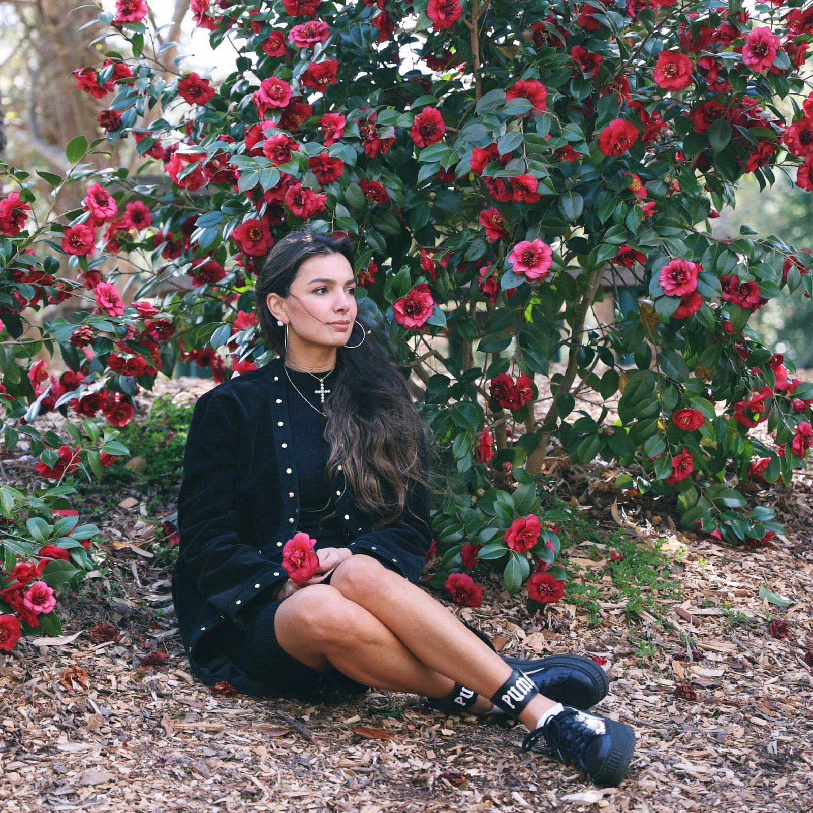 A woman peacefully meditating outdoors surrounded by blooming red clover plants.