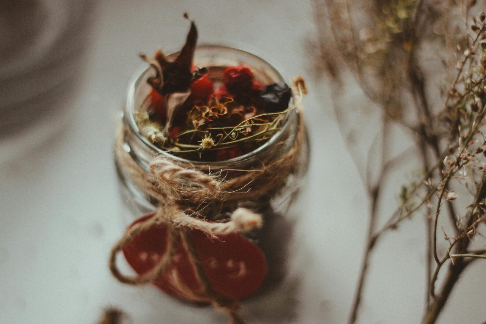 A steaming cup of red clover tea next to dried herbs and a jar labeled 'Red Clover.'
