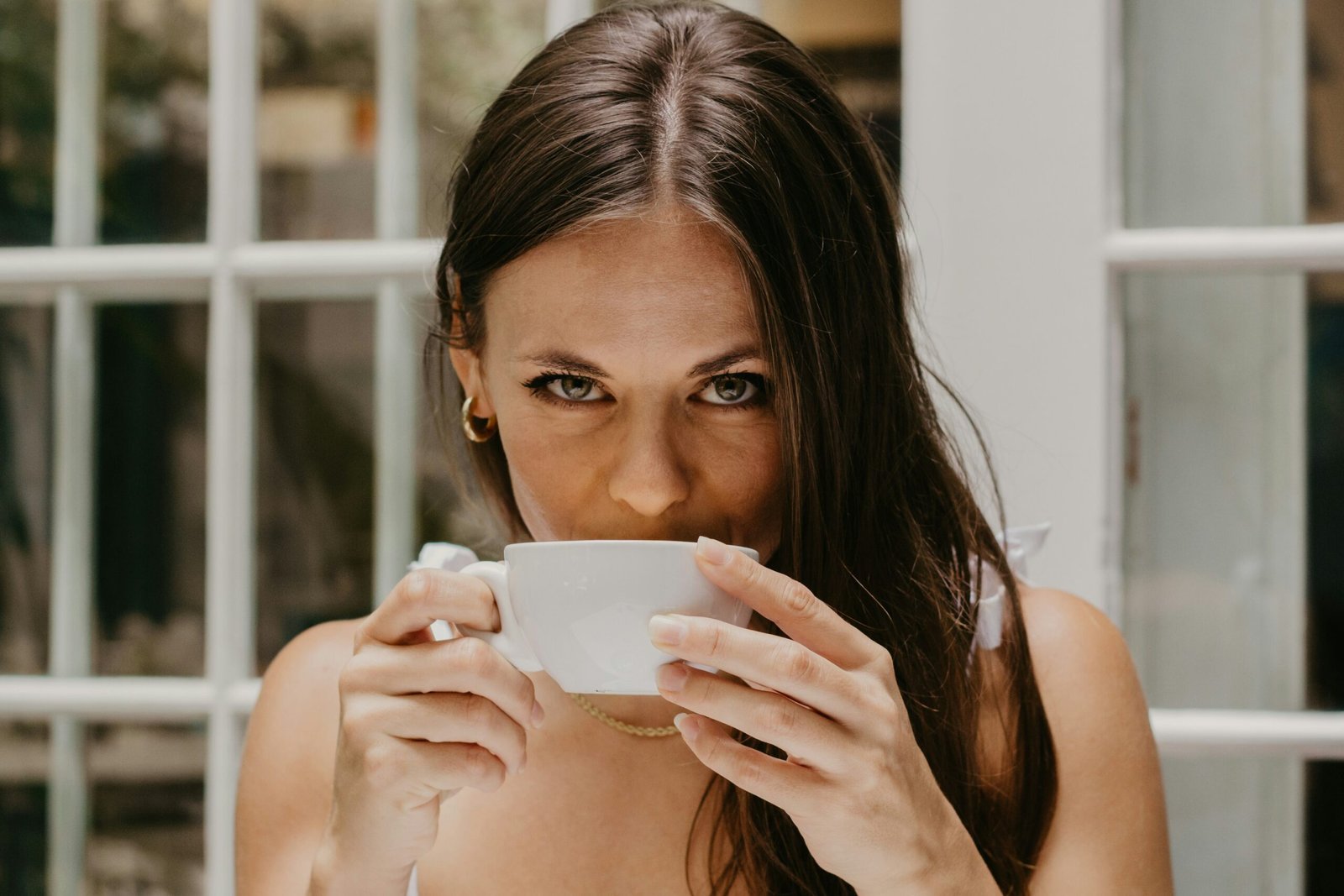 Smiling woman holding mug of red clover tea next to yoga mat