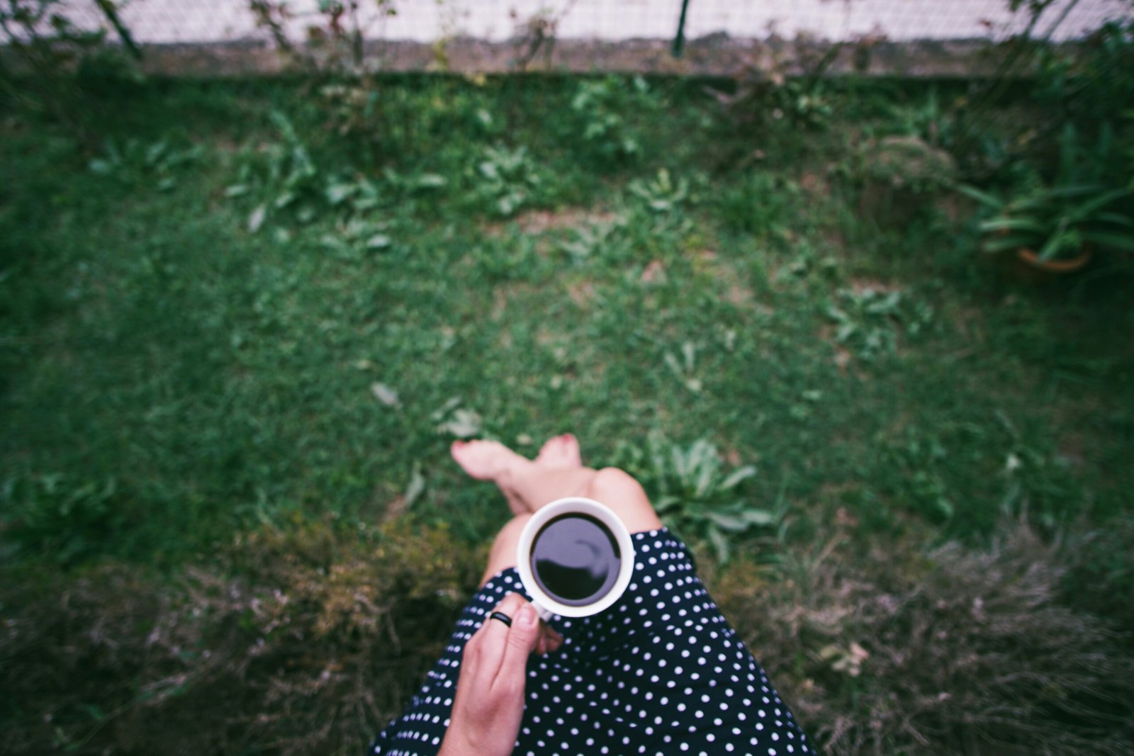 Woman drinking red clover tea outdoors surrounded by fresh greenery