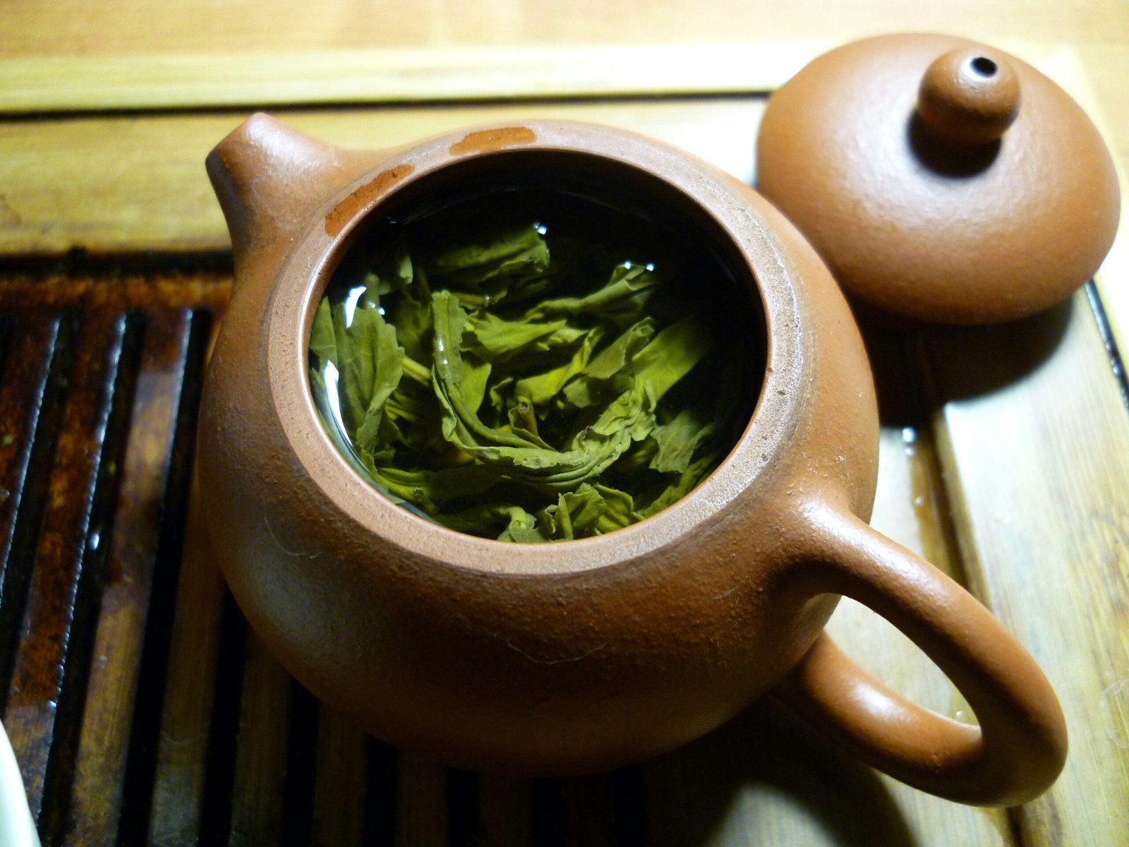 A steaming cup of red clover tea surrounded by dried flower petals